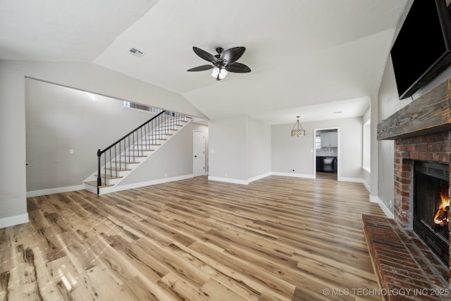 unfurnished living room featuring visible vents, stairway, a fireplace, and wood finished floors