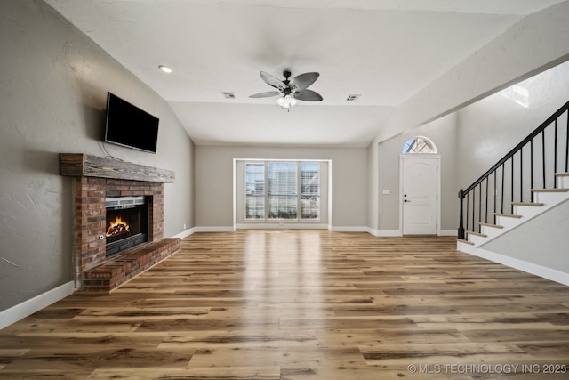 unfurnished living room featuring stairway, wood finished floors, and vaulted ceiling