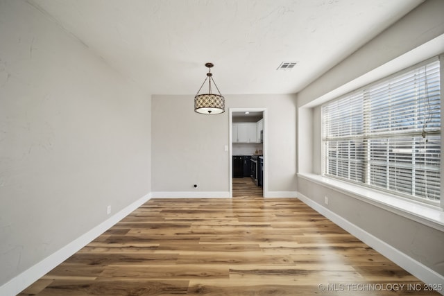 unfurnished dining area with visible vents, baseboards, and wood finished floors