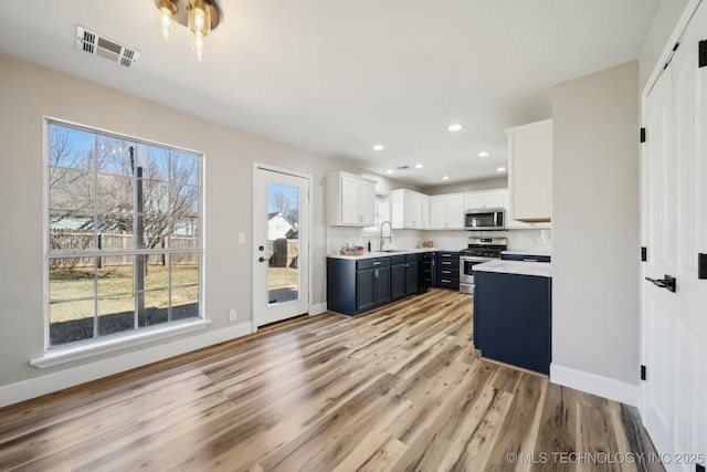 kitchen with a healthy amount of sunlight, visible vents, stainless steel appliances, light countertops, and light wood-type flooring