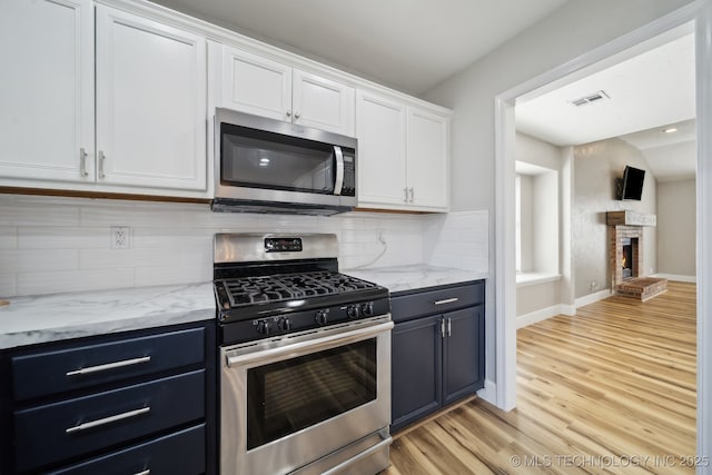 kitchen featuring tasteful backsplash, white cabinets, stainless steel appliances, and blue cabinets