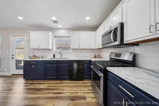 kitchen featuring a sink, blue cabinetry, tasteful backsplash, white cabinetry, and stainless steel appliances