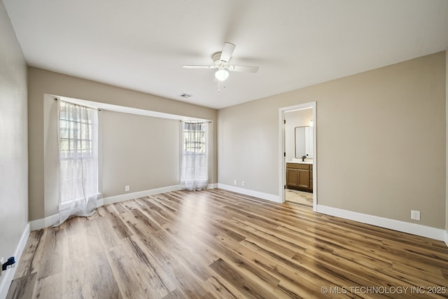 empty room with visible vents, light wood-style flooring, a ceiling fan, a sink, and baseboards