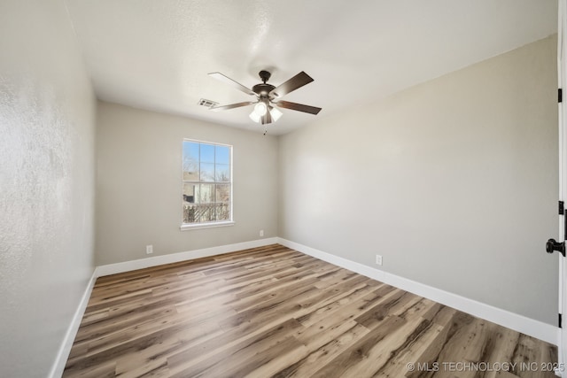 spare room featuring visible vents, baseboards, wood finished floors, and a ceiling fan