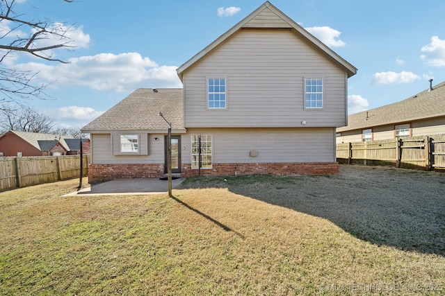 rear view of property with a yard, a patio area, and a fenced backyard