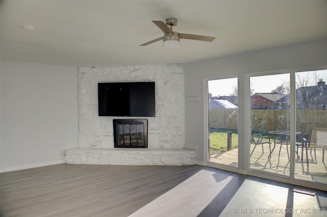 living area featuring a ceiling fan, wood finished floors, a fireplace, and baseboards