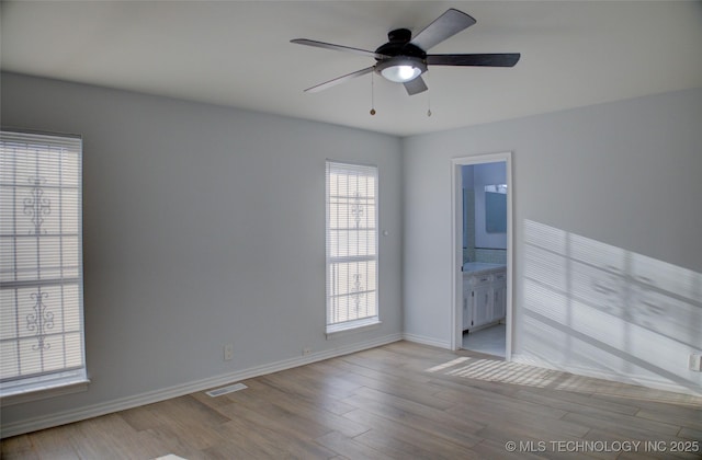 unfurnished room featuring visible vents, a ceiling fan, baseboards, and wood finished floors