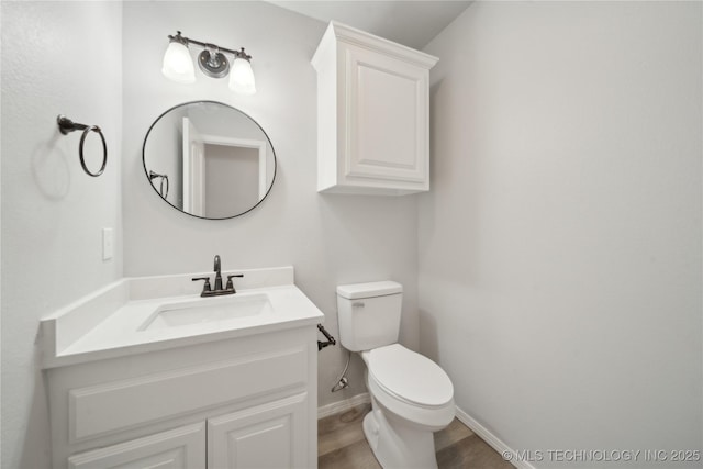 half bath featuring toilet, vanity, and baseboards