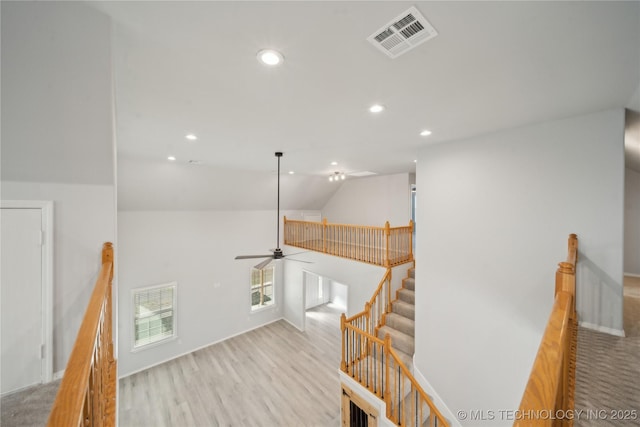 staircase with vaulted ceiling, wood finished floors, recessed lighting, and visible vents