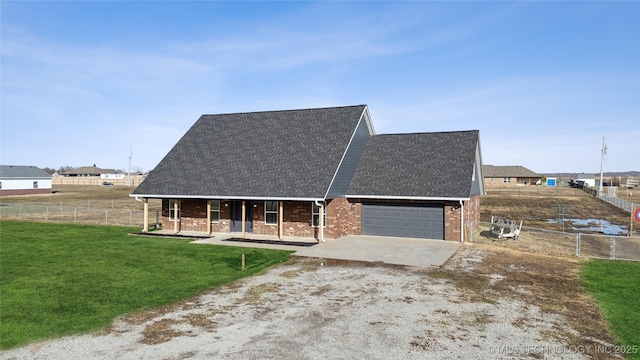 view of front of home with brick siding, concrete driveway, a front yard, and fence