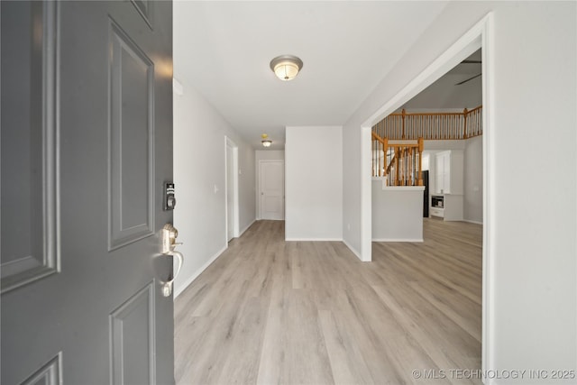 entryway with stairway, light wood-style flooring, and baseboards