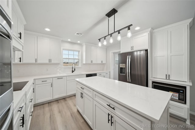 kitchen with decorative backsplash, white cabinetry, black appliances, and a sink