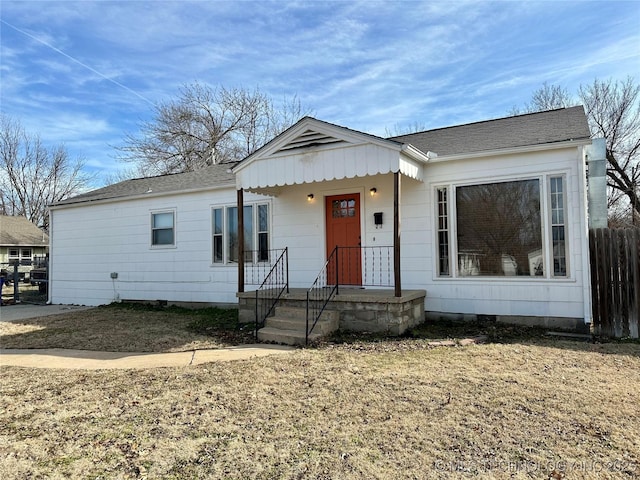 view of front of home with crawl space, a shingled roof, and fence