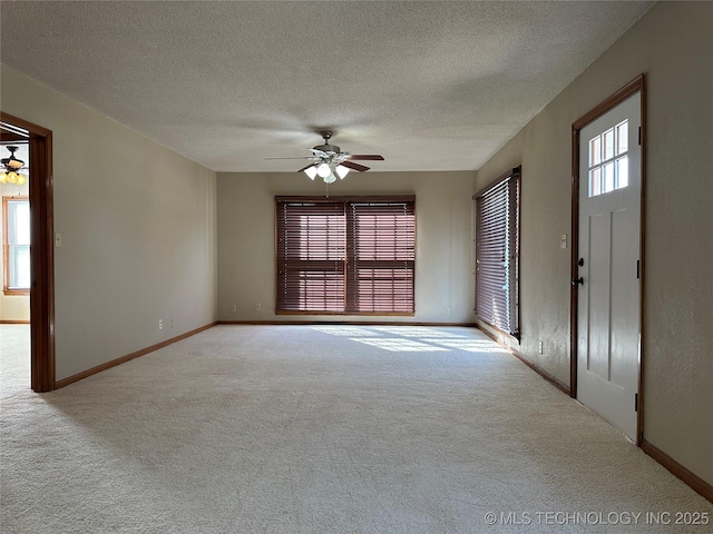 interior space featuring a textured ceiling, carpet flooring, baseboards, and ceiling fan