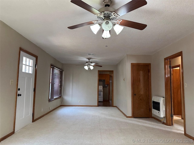 unfurnished living room featuring visible vents, heating unit, a textured ceiling, baseboards, and light colored carpet