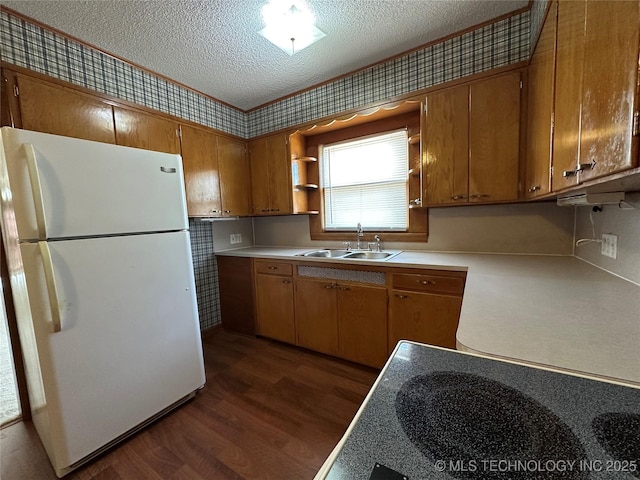 kitchen featuring a sink, a textured ceiling, light countertops, and freestanding refrigerator