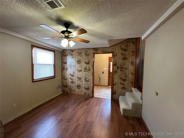 spare room with wood finished floors, baseboards, visible vents, ceiling fan, and a textured ceiling