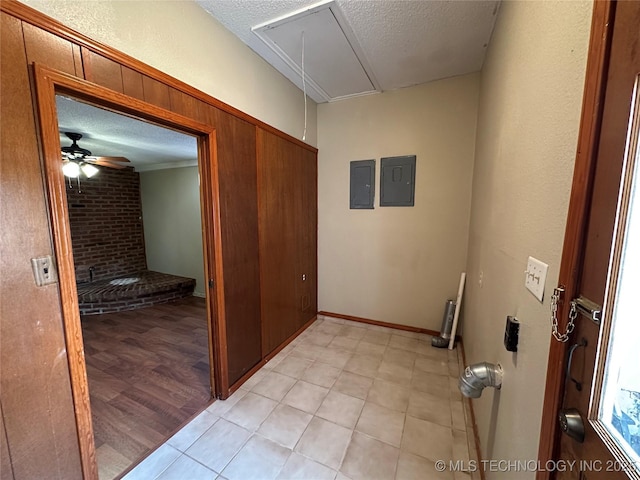 hallway featuring electric panel, a textured ceiling, and attic access