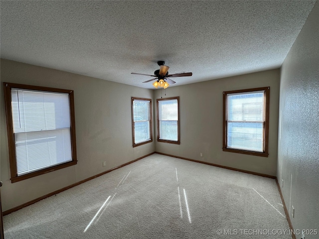 empty room featuring light colored carpet, a textured ceiling, and baseboards