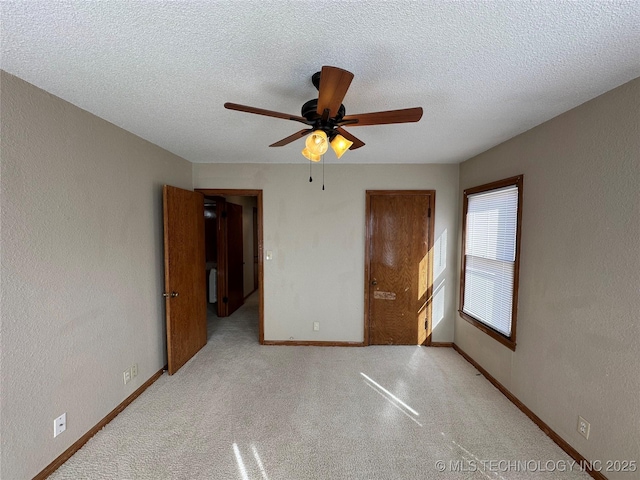 unfurnished bedroom with a textured ceiling, carpet, baseboards, and a textured wall