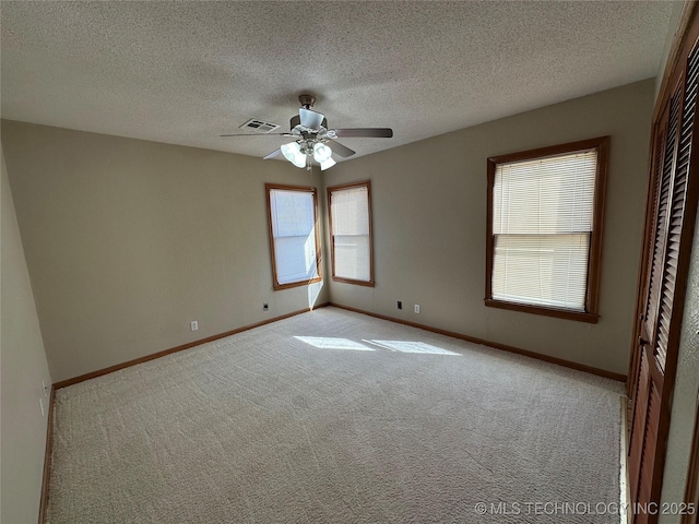 carpeted empty room featuring visible vents, ceiling fan, a textured ceiling, and baseboards