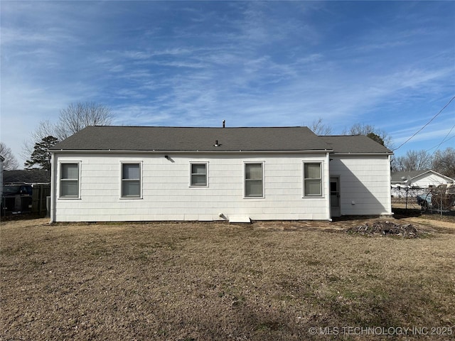 rear view of house featuring a lawn and fence