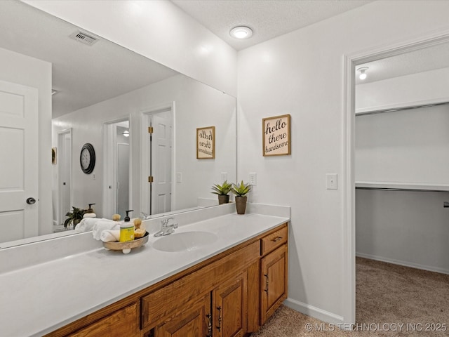 bathroom with visible vents, a textured ceiling, vanity, and baseboards