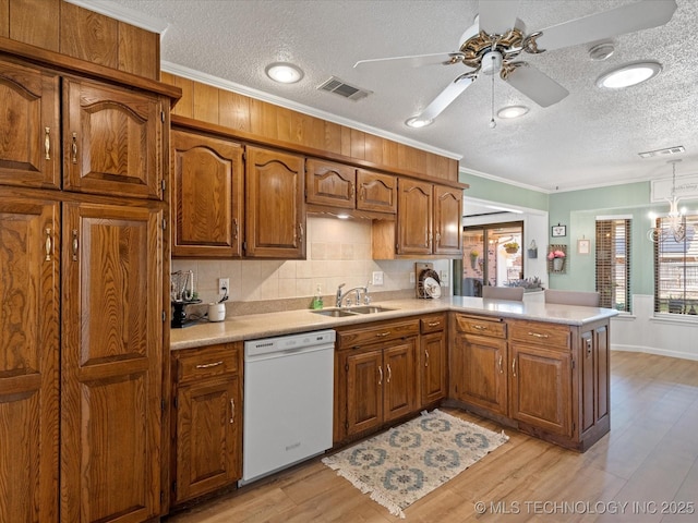 kitchen featuring a healthy amount of sunlight, a textured ceiling, visible vents, white dishwasher, and a sink
