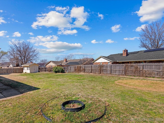 view of yard featuring a storage unit, a fenced backyard, and an outbuilding