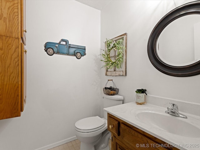 half bathroom with vanity, toilet, and baseboards