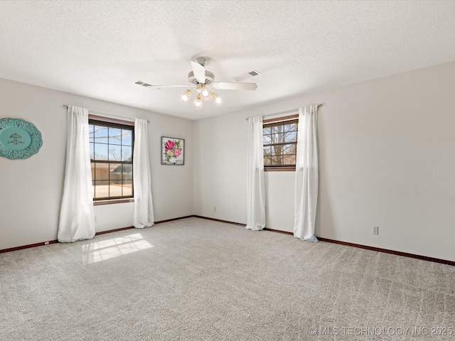 carpeted spare room with a healthy amount of sunlight, visible vents, and ceiling fan