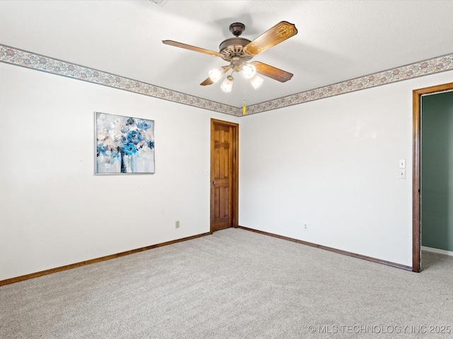 carpeted spare room featuring baseboards and ceiling fan