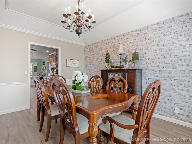 dining area with brick wall, crown molding, baseboards, light wood-style floors, and an inviting chandelier