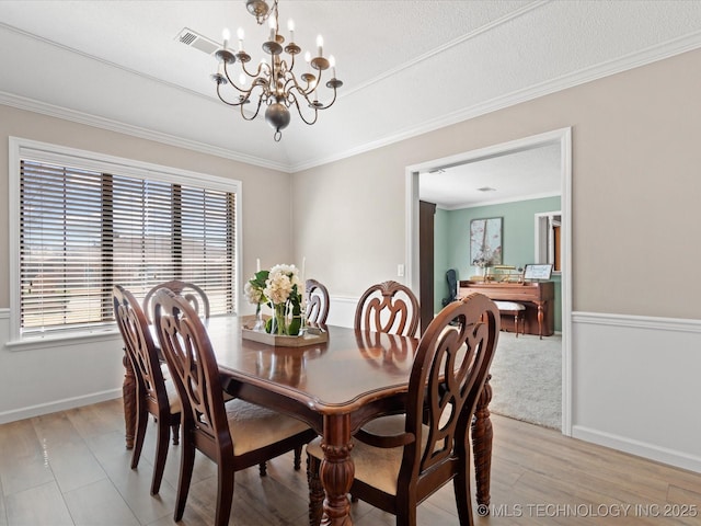 dining area with an inviting chandelier, light wood-style floors, baseboards, visible vents, and ornamental molding