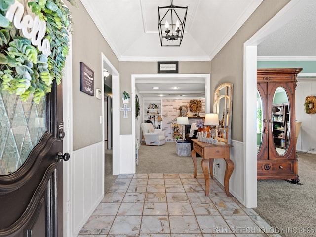 entrance foyer with crown molding, wainscoting, lofted ceiling, light carpet, and a chandelier