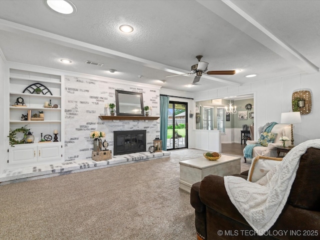living room featuring a textured ceiling, visible vents, a large fireplace, carpet floors, and ceiling fan with notable chandelier