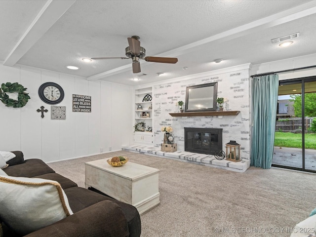 carpeted living room featuring a ceiling fan, a textured ceiling, visible vents, and a fireplace