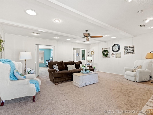 living area featuring visible vents, carpet flooring, ceiling fan, and beamed ceiling