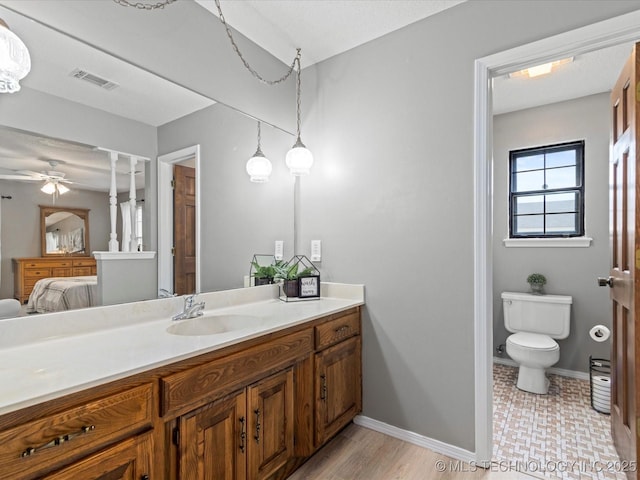 ensuite bathroom with visible vents, vanity, baseboards, toilet, and ensuite bath