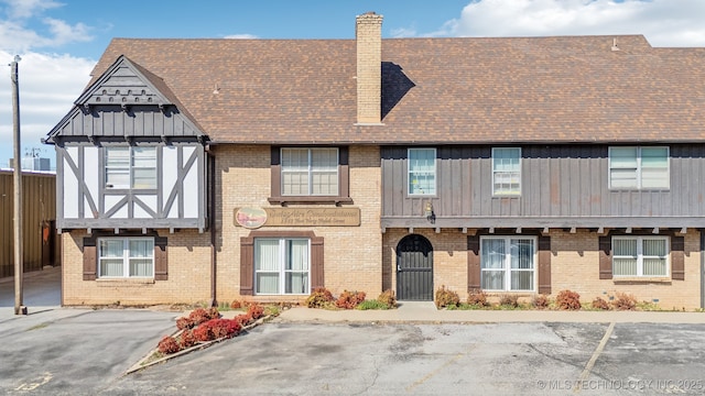 townhome / multi-family property with uncovered parking, brick siding, and a chimney