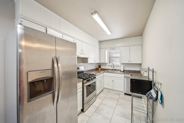 kitchen with under cabinet range hood, light tile patterned floors, stainless steel appliances, white cabinetry, and a sink