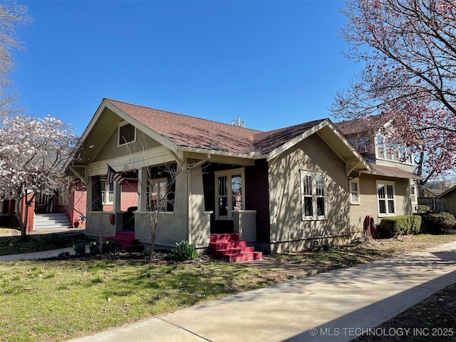 bungalow-style home featuring stucco siding, a porch, and a front yard