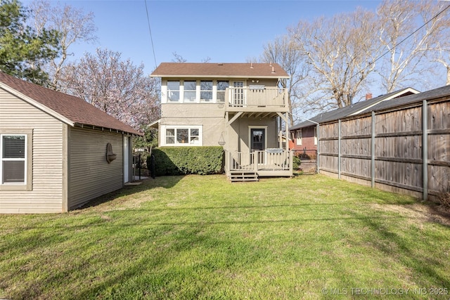 rear view of house with a balcony, a lawn, fence, and a wooden deck