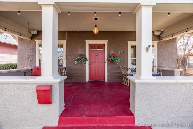 doorway to property featuring stucco siding and a porch