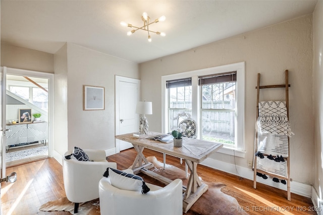 home office featuring baseboards, an inviting chandelier, and wood finished floors