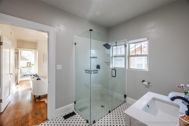 full bath featuring baseboards, vanity, wood finished floors, and a shower stall