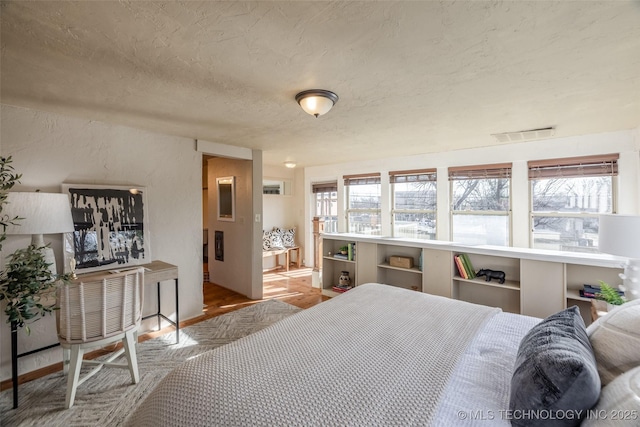 bedroom with a textured wall, visible vents, and a textured ceiling