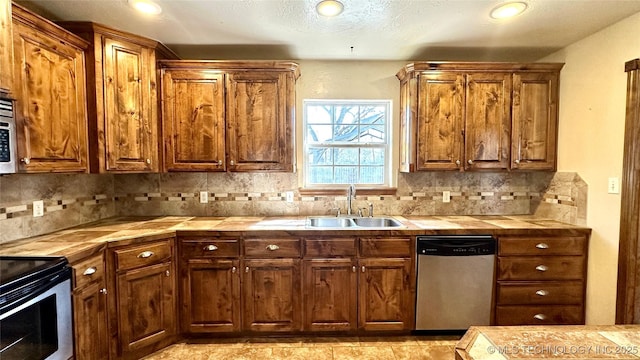 kitchen with a sink, stainless steel appliances, backsplash, and tile countertops