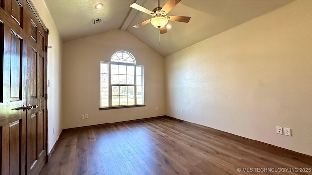 spare room featuring a ceiling fan, visible vents, baseboards, dark wood finished floors, and vaulted ceiling with beams