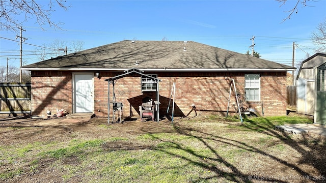 back of property with a yard, brick siding, and a shingled roof